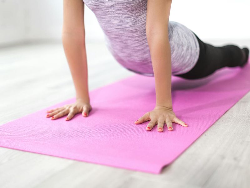 Person performing a seated yoga stretch on a mat.